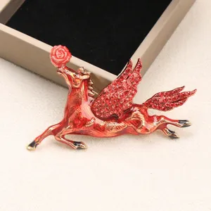 Detailed view of red rhinestone pegasus brooch with enamel finish and gold accents