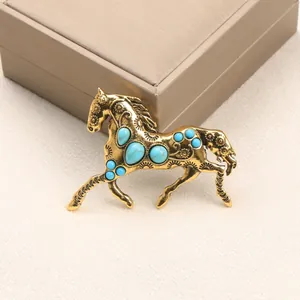 Detailed close-up of vintage golden horse brooch with turquoise stone inlays on jewelry box