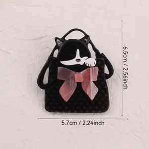 Macro view of creative acrylic brooch featuring a cat in a polka-dot bag with pink bow