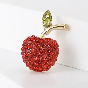 Macro detail view of a sparkling red crystal apple brooch with a polished gold-tone finish