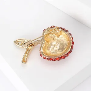 Detailed macro view of the back structure and pin of a red rhinestone apple brooch.