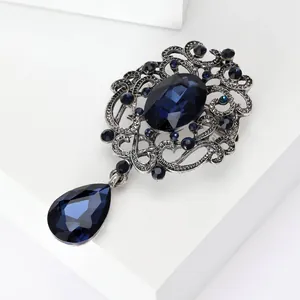 Close-up of vintage crystal brooch with dark blue teardrop pendant in silver tone