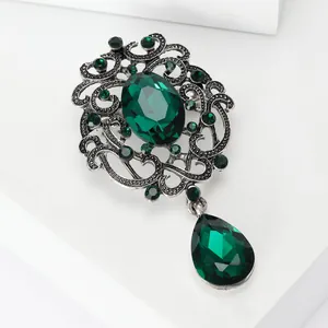 Detailed view of a vintage silver brooch featuring emerald green crystal and teardrop