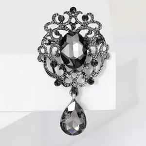Close-up of a vintage silver brooch with black crystals and a teardrop pendant detail