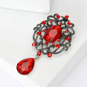 Detailed view of a vintage alloy brooch with vibrant red crystals and ornate silver-toned metalwork