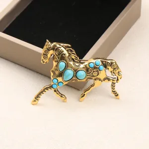 Vintage antique gold horse brooch with turquoise stones, elegant coat pin accessory.