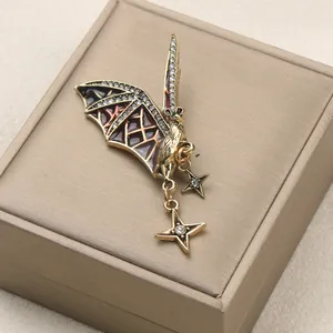 Close-up of a vintage bat brooch with rhinestones and star charms on a jewelry box.
