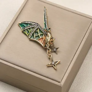Vintage gold-tone bat brooch with green enamel wings and star pendants
