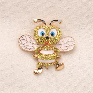 Dettaglio di una spilla a forma di ape con strass gialli brillanti e smalto bianco