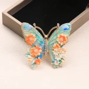 Vintage-Schmetterlingsbrosche mit bunten Strassblumen auf elegantem beigem Grund.