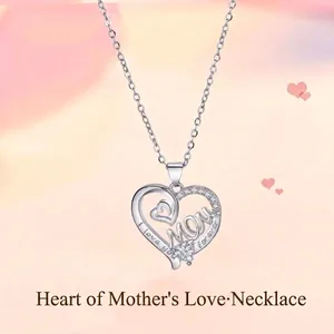 Detail van een zilveren hartketting met 'MOM' gravure en schitterende steentjes