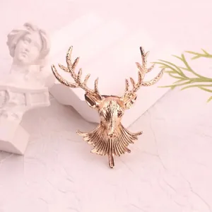 Close-up of a vintage golden stag head brooch with intricate textured antler details.