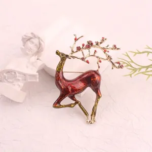 Detailed view of elegant red enamel deer brooch with golden antlers and flower accents.