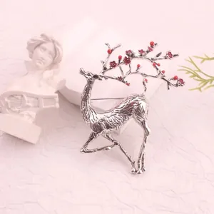 Detailed macro view of vintage silver-plated enamel deer brooch with red floral antlers