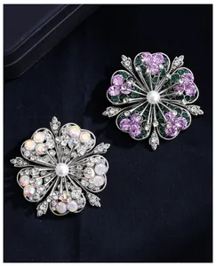 Detailansicht eleganter Blumenbrosche mit lila Kristallen und zentralen Perlen.