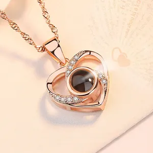 Detailopname van de roségouden hartprojectieketting met 100 talen Ik hou van jou