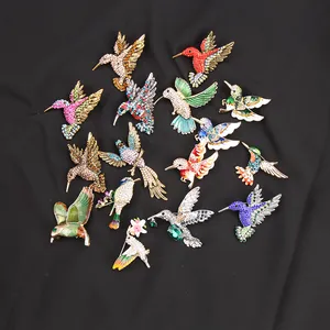 Levendige kolibrie broches met strass en emaille op zwarte stoffen achtergrond