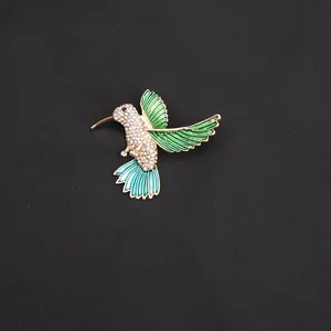 Detailopname van een elegante kolibrie broche met fonkelende kristallen en groen email.