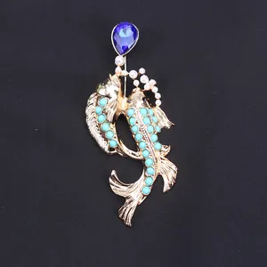 Detail of gold-tone koi fish brooch with blue crystal and turquoise beads