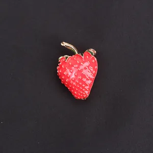 Detailed macro view of a vibrant red strawberry enamel brooch with gold-tone metal stem
