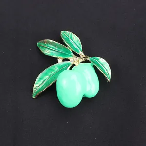 Macro detail of a green mango fruit brooch with gold trim and green enamel finish.