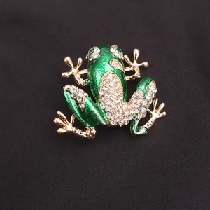 Gedetailleerd zicht op een elegante groene strass kikker broche op zwarte textuur stof