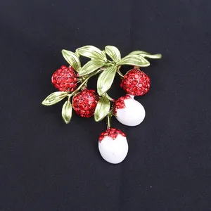 Detailed view of a fruit-shaped lychee brooch with red rhinestones and white fruit beads.