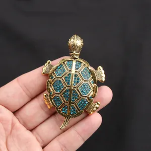 Dettaglio di un'elegante spilla tartaruga vintage dorata con cristalli blu brillanti