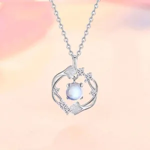 Detailopname van een elegante zilveren ketting met ginkgo blad en maansteen hanger