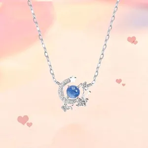 Detailopname van een zilveren ketting met maan en sterren hanger en blauwe kraal