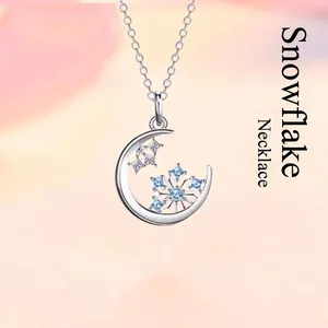 Elegante zilveren halve maan halsketting met een delicate blauwe kristallen sneeuwvlok hanger.
