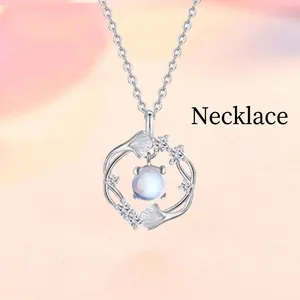 Detail of silver ginkgo leaf pendant necklace with a glowing round faux moonstone
