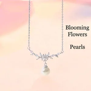Detailopname van een zilveren bloemen-kristallen ketting met een witte parelhanger