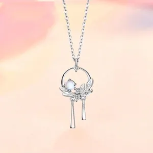 Detailed close-up of a silver necklace featuring a moonstone leaf pendant and tassels
