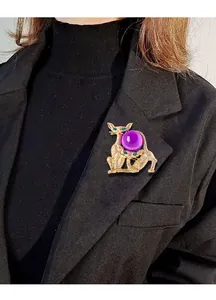 Gros plan d'une broche vintage avec orbe en verre violet et motif de chat doré.