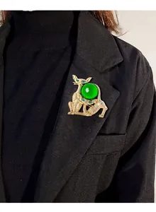 Détail d'une broche vintage chat et caniche avec une grande boule de verre vert gelée.
