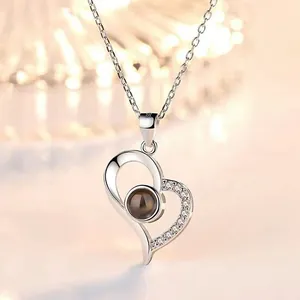 Detailed macro view of silver heart projection necklace featuring sparkling crystal accents.
