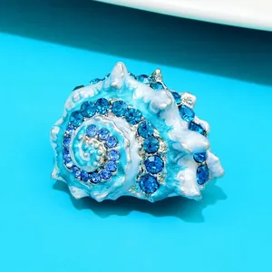Detail van een zeeschelp broche met blauw emaille en fonkelende strass-steentjes