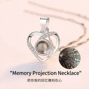 Close-up of a silver heart projection necklace featuring I Love You in 100 languages.