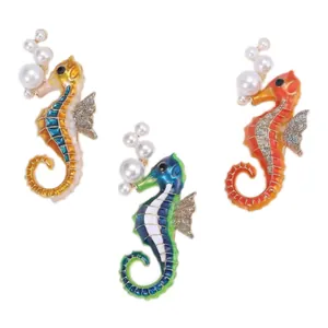 Detailed view of three colorful enamel seahorse brooches with pearl accents