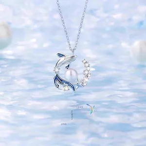 Elegante zilveren dolfijn hanger ketting met parel en fonkelende stenen op water achtergrond