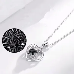 Detailed view of a silver heart projection necklace featuring I love you in 100 languages