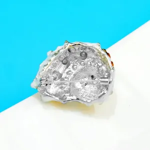 Detailweergave van de achterkant van een zilverkleurige schelpspeld met pinsluiting.
