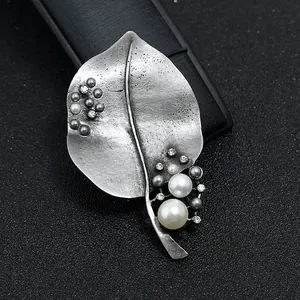 Detailopname van een vintage bladzilveren broche met witte parels en strass