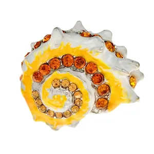 Gedetailleerde opname van een emaille schelpbrosche met oranje kristalaccenten
