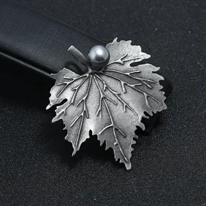 Gedetailleerde close-up van een vintage bladbroche met antieke zilveren afwerking