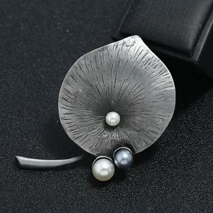 Detailopname van een retro broche met antieke tinnen afwerking en parels.