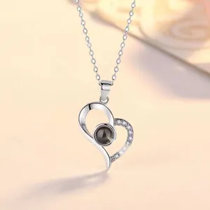 Close-up of a silver heart pendant necklace featuring a 100-language projection stone.