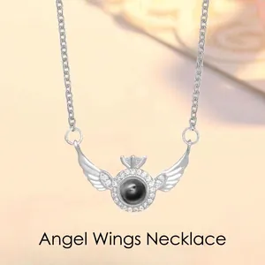 Detailed view of silver-tone angel wings projection necklace with stone pendant
