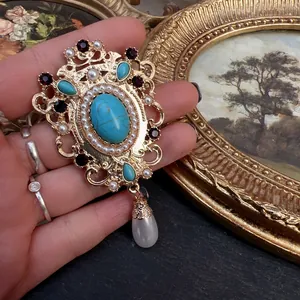 Close-up of a vintage baroque style brooch with turquoise, pearls, and crystals details.